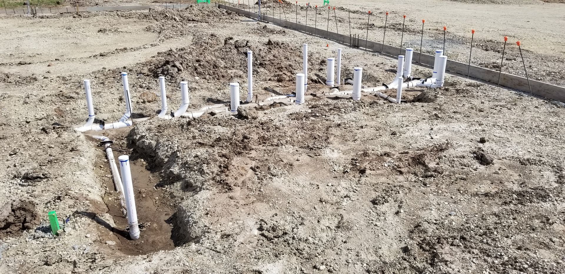 Pipes installed in the ground, awaiting final connections in a construction site.