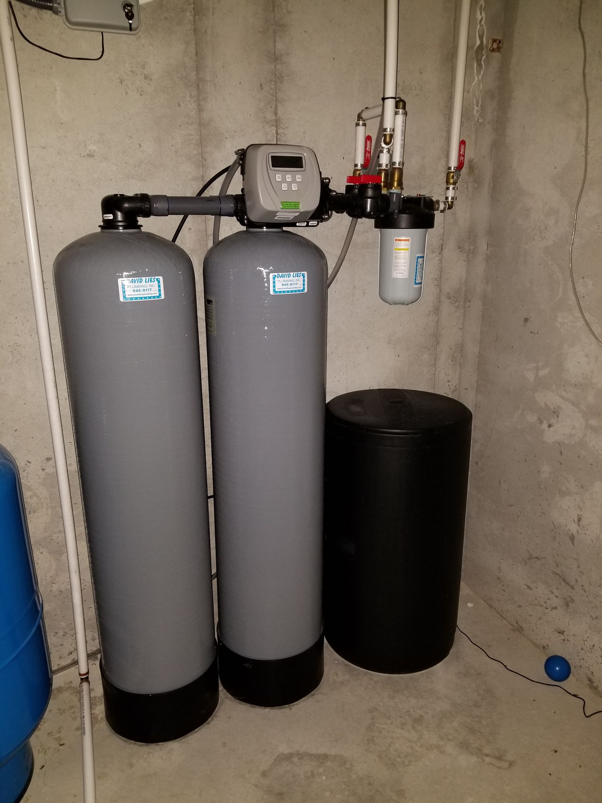 Water filtration system in a concrete basement. Includes tanks, control unit, and filter.
