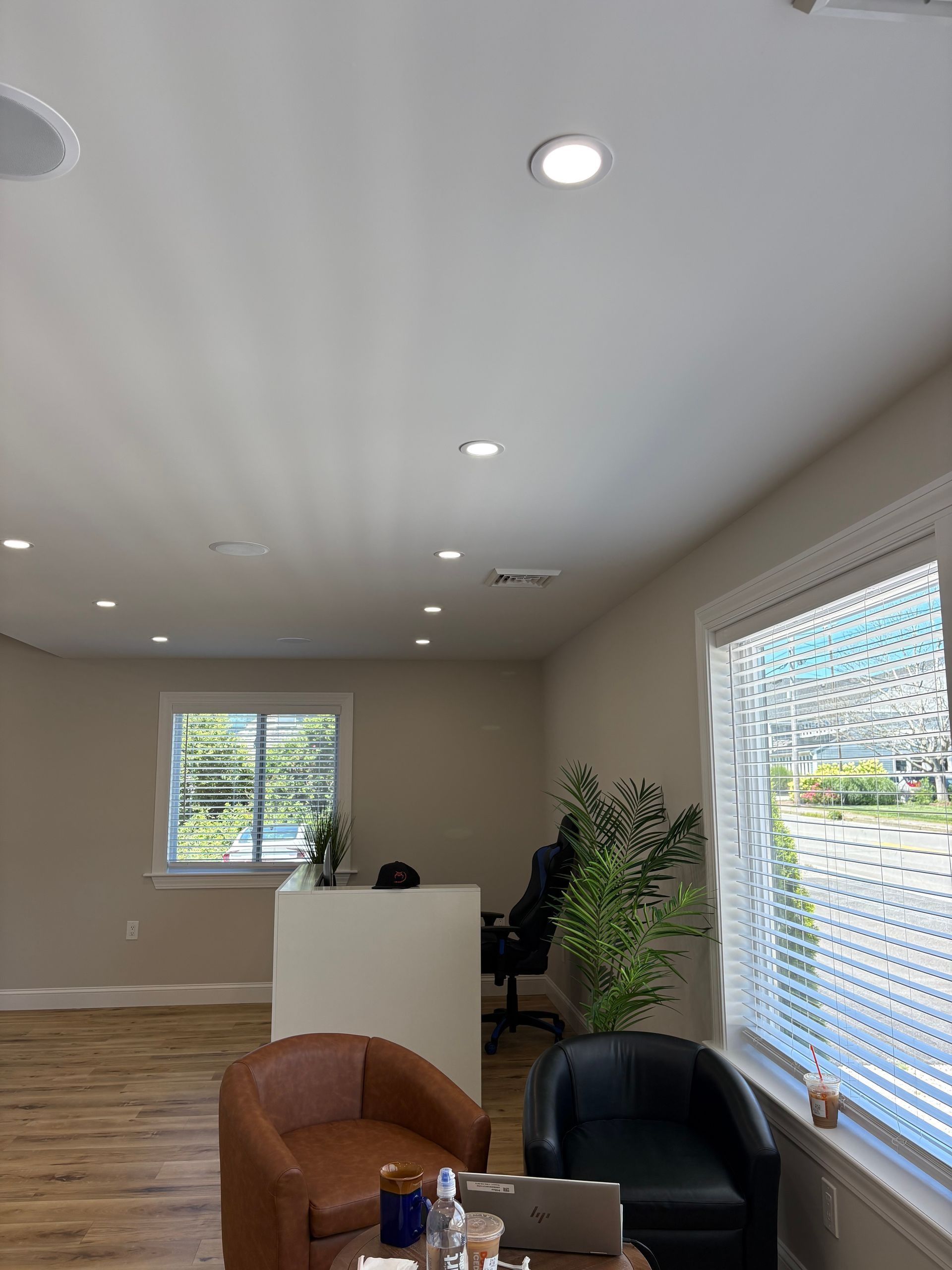 Bright office waiting area with brown leather chairs, reception desk, and large windows.