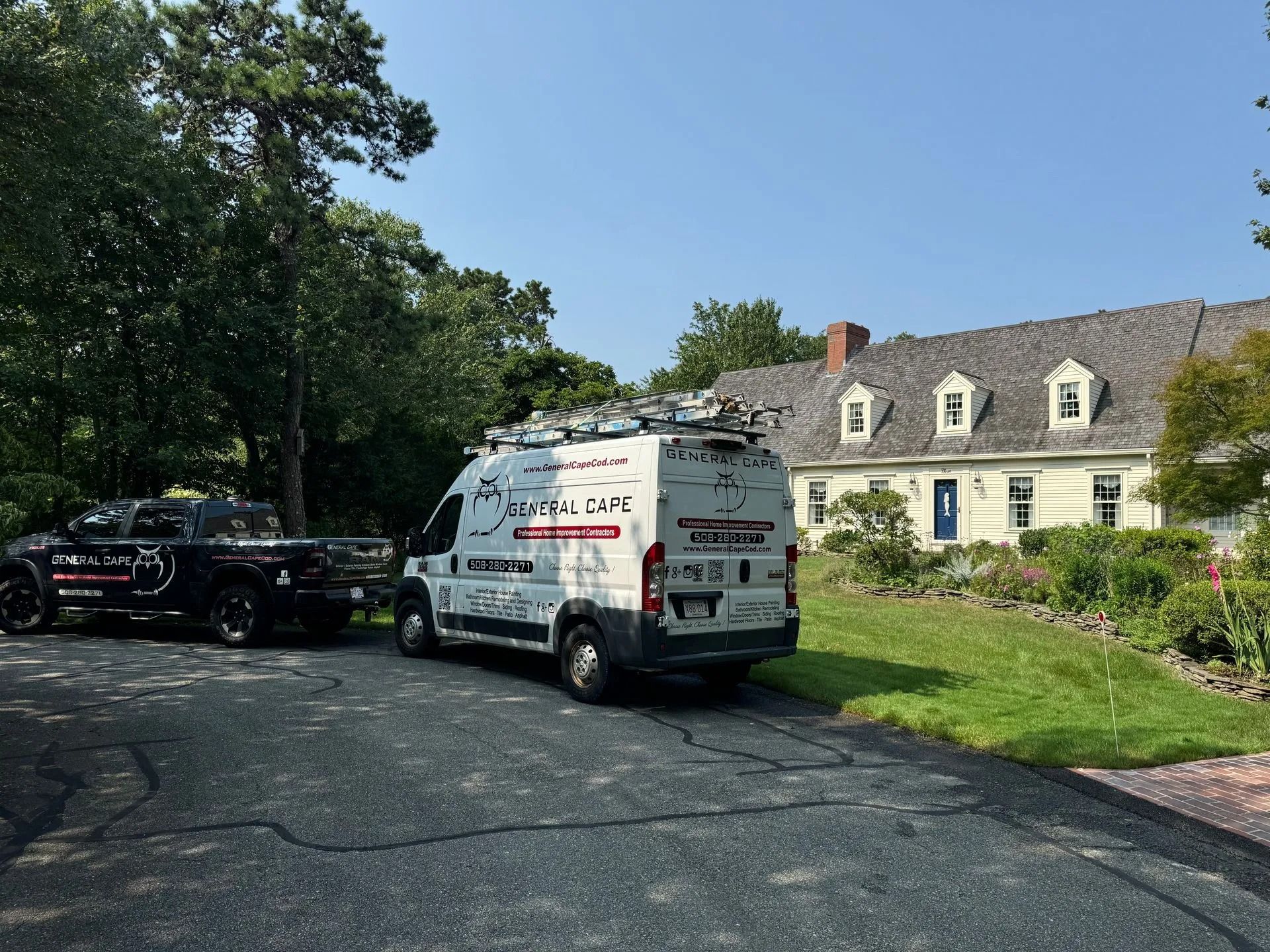White van and black truck parked in front of a house. 