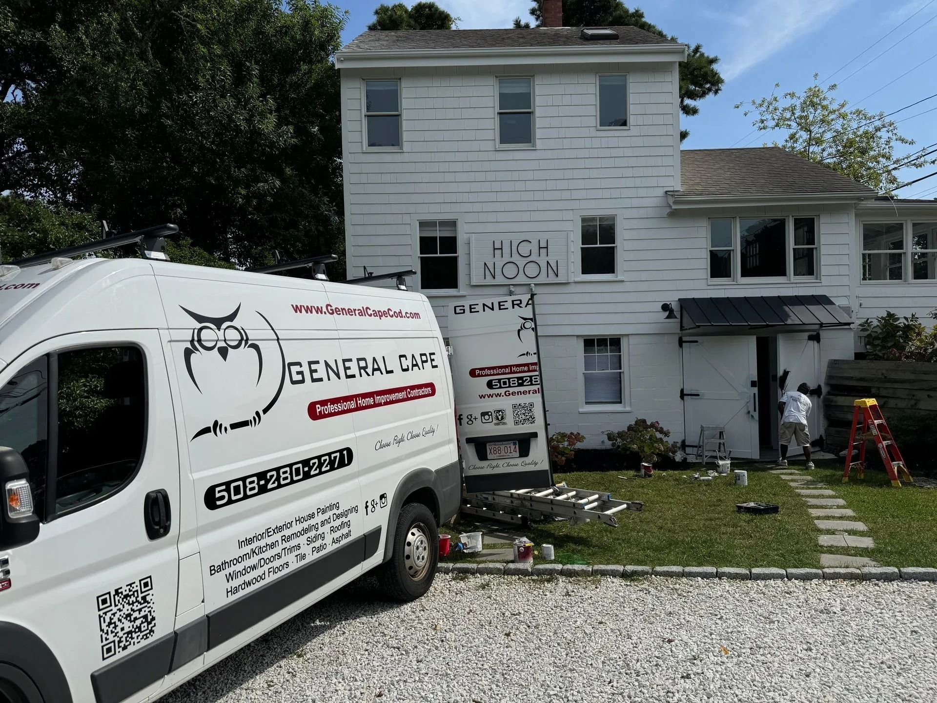 White van with owl logo parked in front of a white building with 