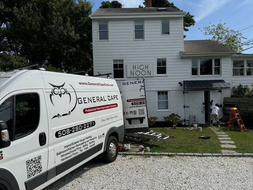 White van with owl logo parked in front of a white building with