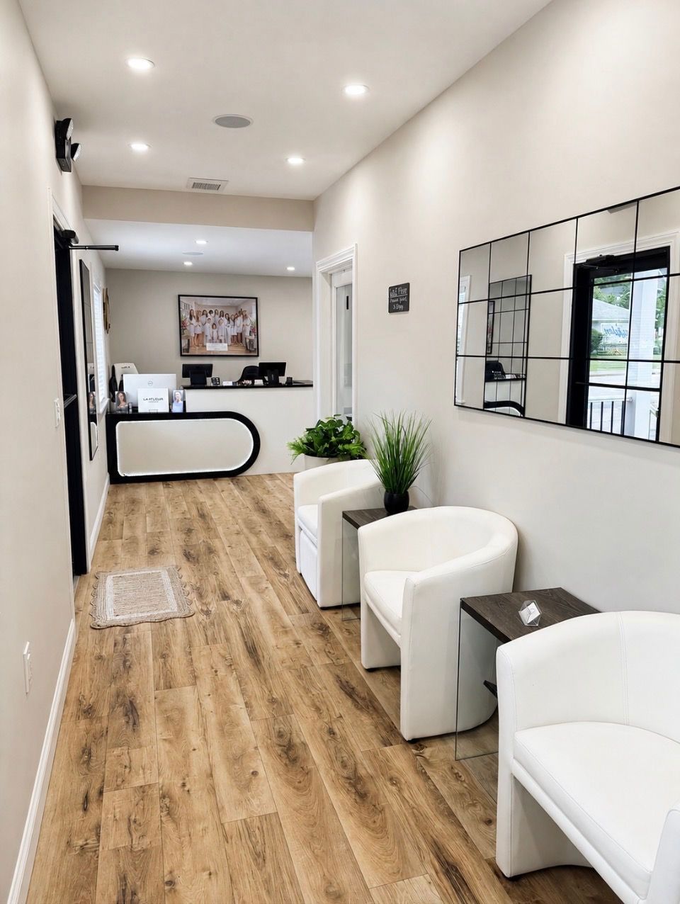 Bright modern waiting room with white chairs, wood floors, plants, and a reception desk