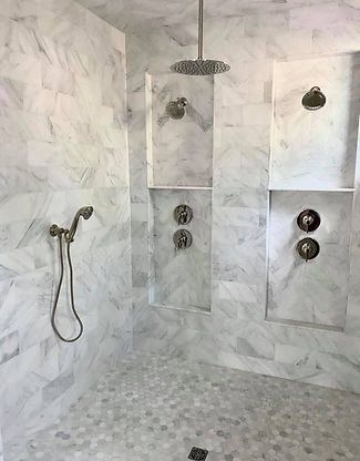 Marble-tiled bathroom with walk-in shower, rain showerhead, handheld sprayer, and mosaic floor.
