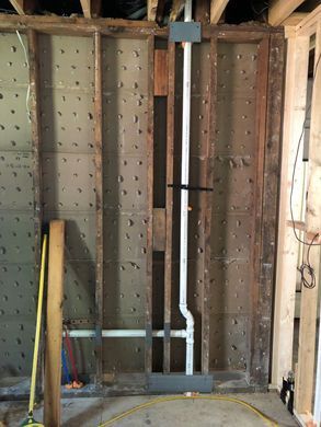 Unfinished basement wall with exposed framing, gray HVAC ducts, and a yellow level leaning against the studs.