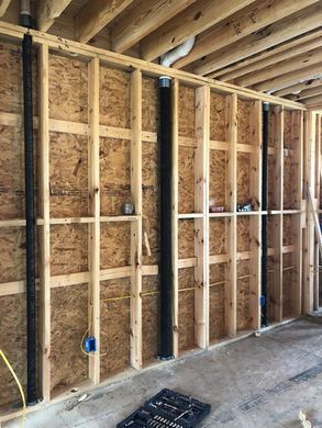 Unfinished room with exposed wooden wall studs, plywood sheathing, and ceiling joists during construction
