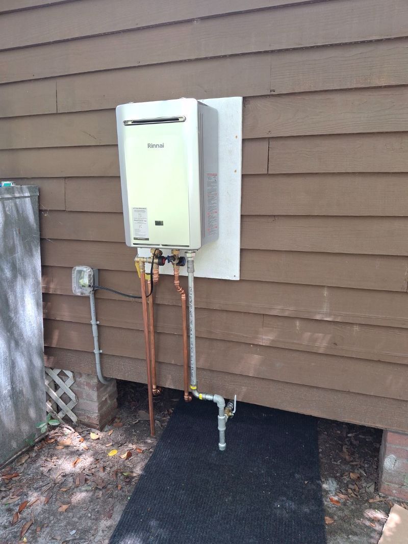 Outdoor tankless water heater with copper pipes mounted on a house exterior wall.