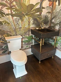 Bathroom with white toilet and black vanity against tropical leaf wallpaper