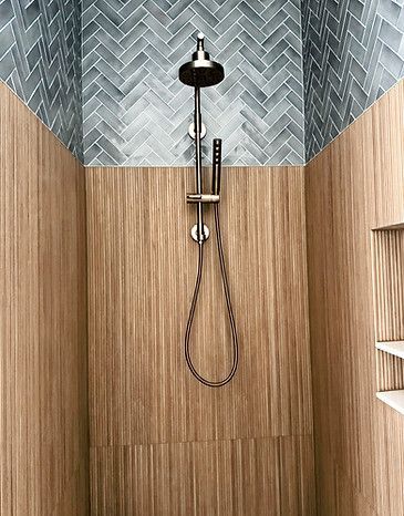 Modern shower with wood-look tile walls and a rain showerhead, handheld wand, and hose.