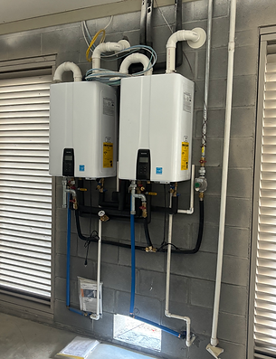 Two white wall-mounted water heaters with pipes in a utility room
