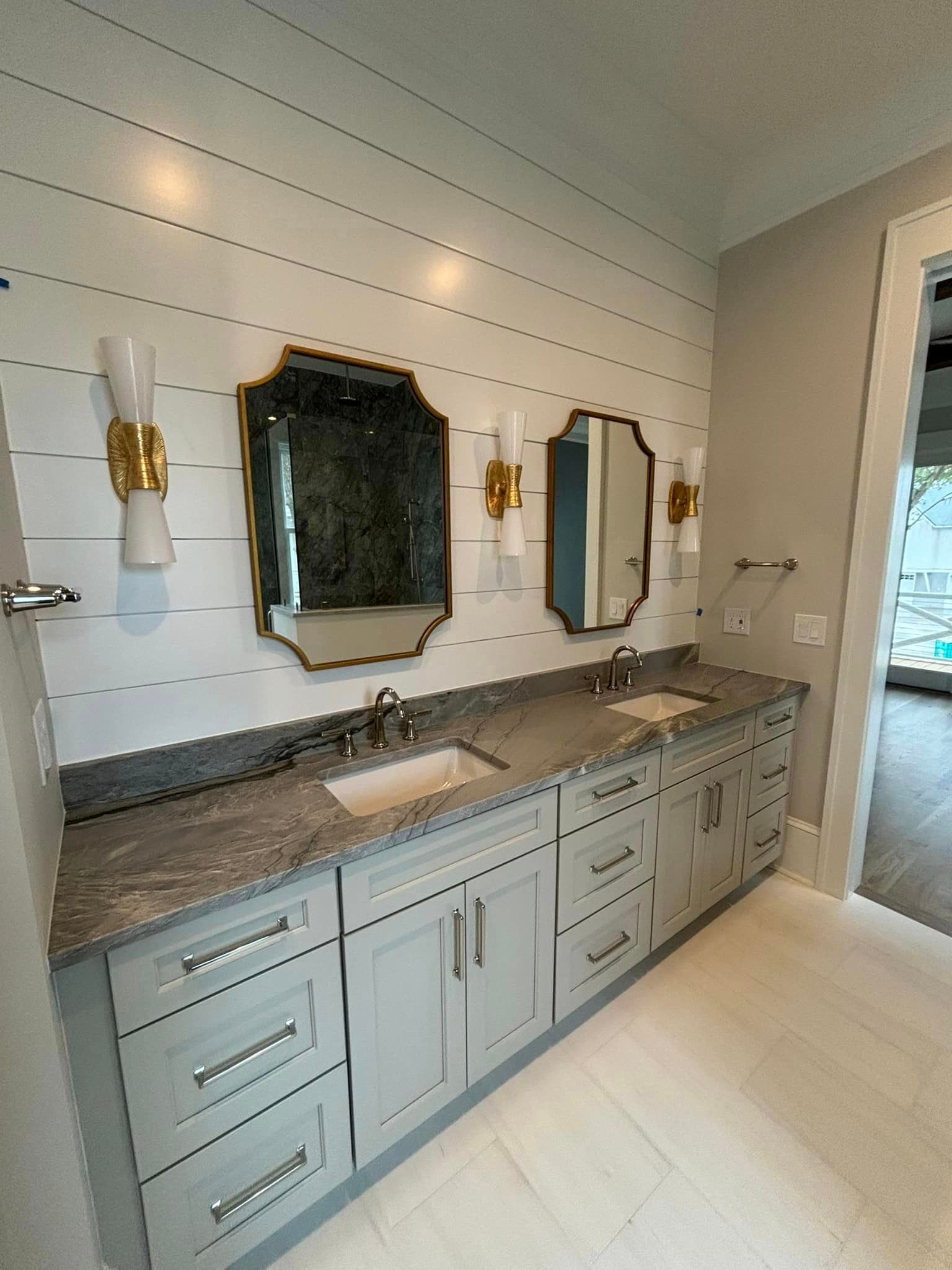 Modern bathroom vanity with granite countertop, mirrors, and white shiplap walls