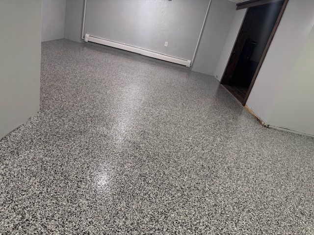 Grey speckled epoxy floor in a room with gray walls and a doorway.