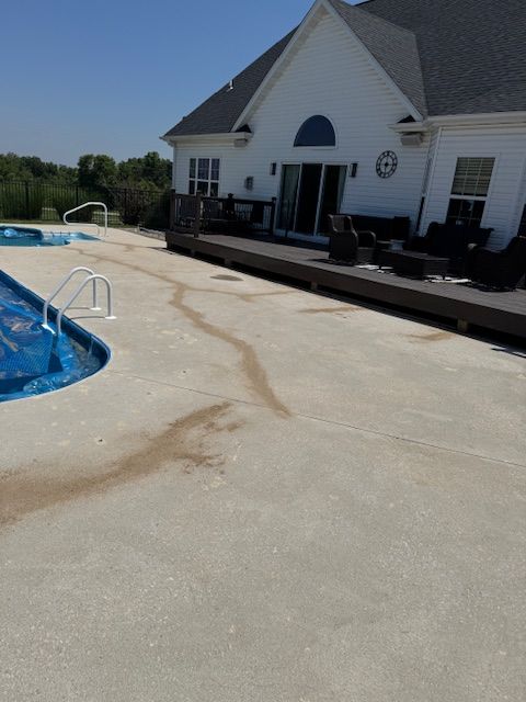 Backyard with a pool and house; brown stains on the concrete pool deck.