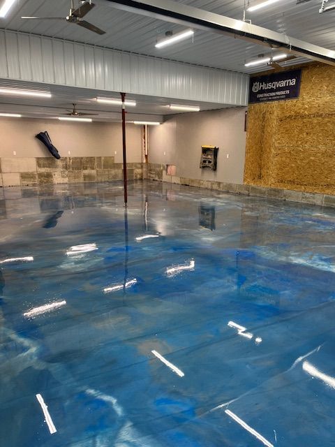 Blue epoxy garage floor, light fixtures. Husqvarna sign on the right.