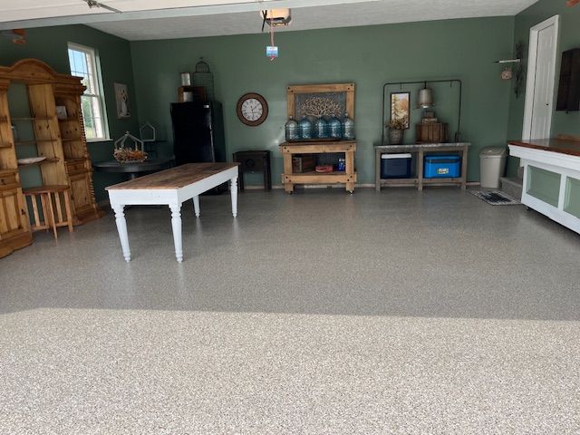 Spacious garage with green walls, a light speckled floor, and various wooden furniture pieces.