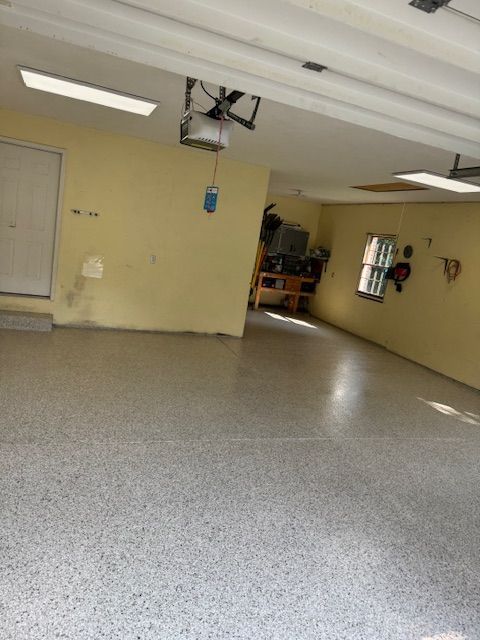 Empty garage with yellow walls, a gray speckled floor, and a closed white door.