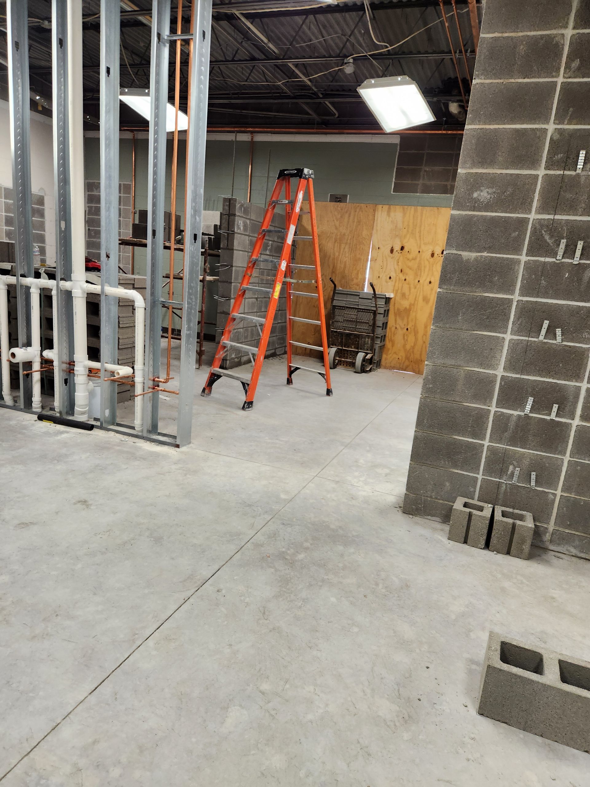 Interior construction site with ladder and exposed wall framing.