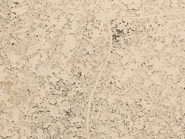 Off-white tile with peeling paint and a curving line.
