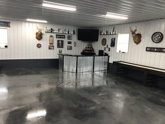 A finished garage with a bar, shuffleboard, taxidermy, and decor; metallic gray floor and walls.
