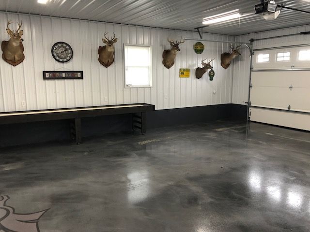 Garage interior with deer mounts, shuffleboard, and epoxy floor.