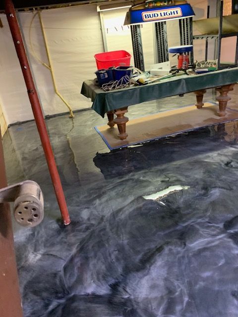 Epoxy-coated basement floor with swirling dark gray and white patterns, pool table in background.