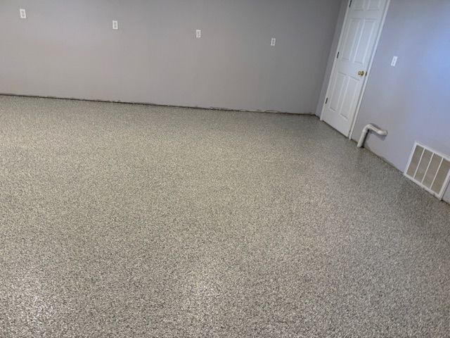 Gray epoxy floor in a room with light gray walls, white door and vent.