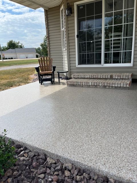A front porch with a gray speckled concrete surface, chair, and sliding glass door.