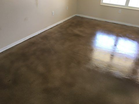 Brown stained concrete floor in a room, with sunlight reflecting off the glossy surface.
