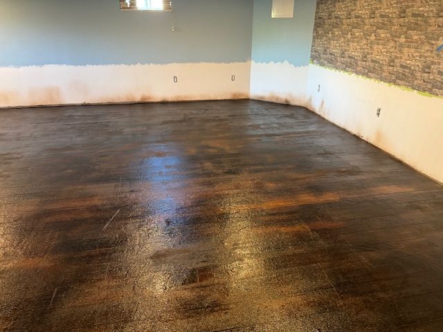 Finished concrete floor with brown and gold hues in a room with blue and brick walls.