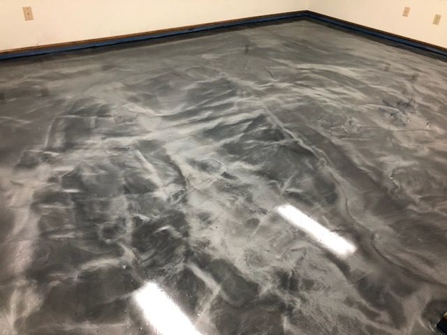 Metallic epoxy floor with swirled silver and gray patterns.