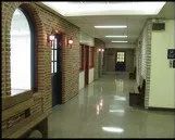 A long hallway with a brick wall and a window in a building.