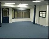 An empty room with a blue carpet and a window.