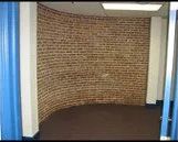 A room with a brick wall and a blue curtain.