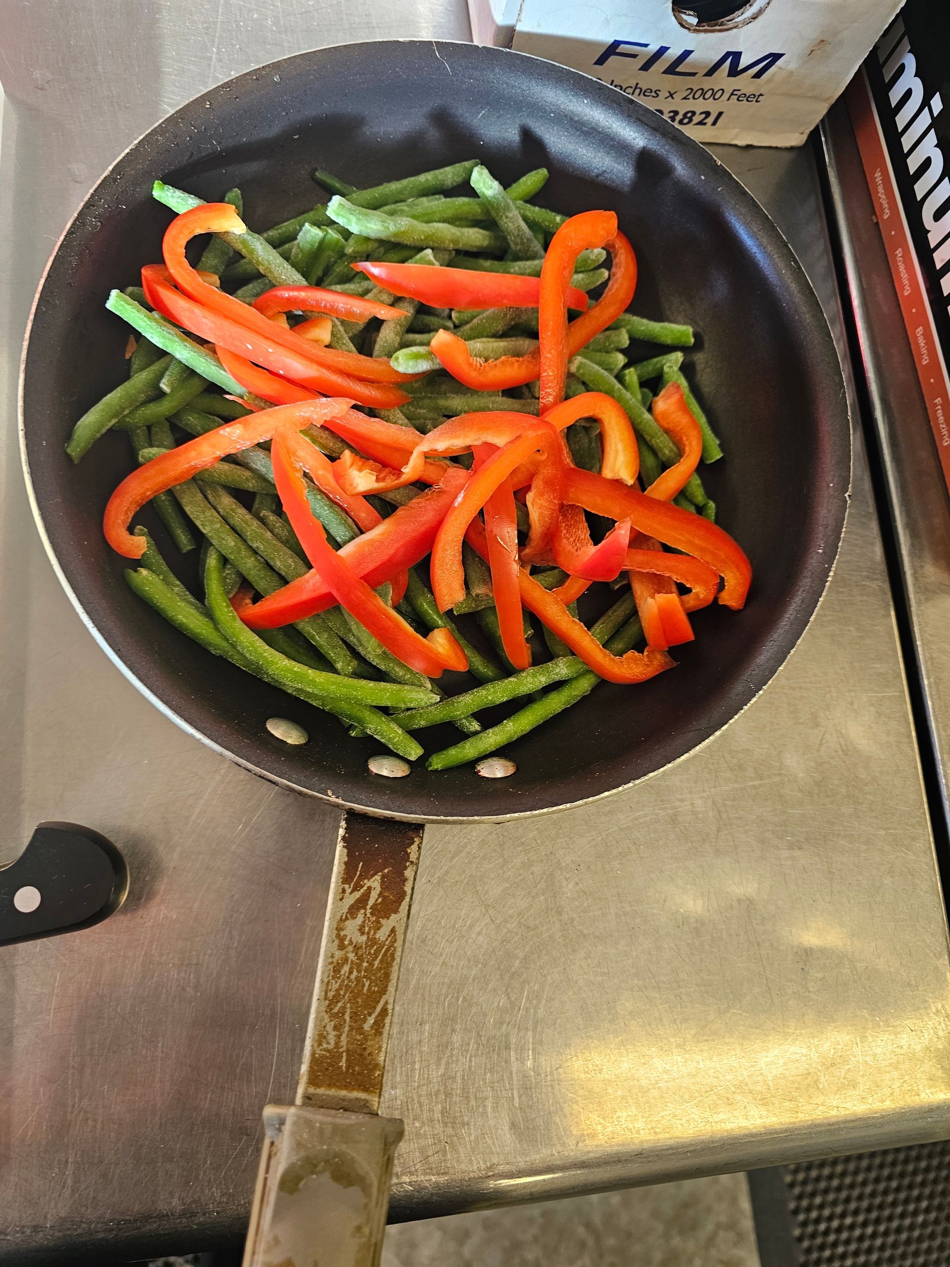 a frying pan filled with green beans and red peppers