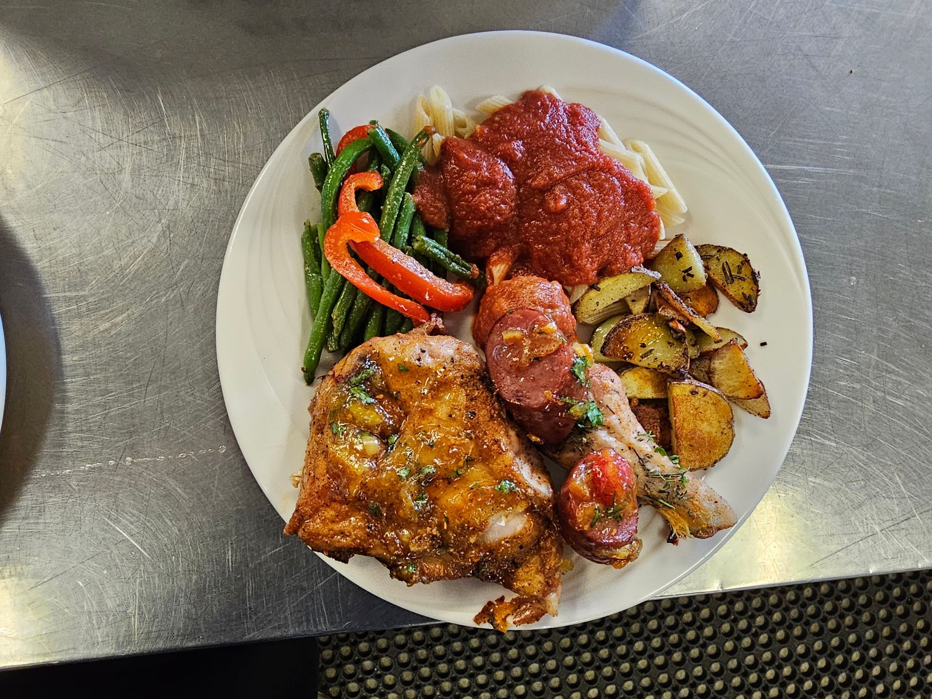 a white plate topped with meat , vegetables and sauce on a table .