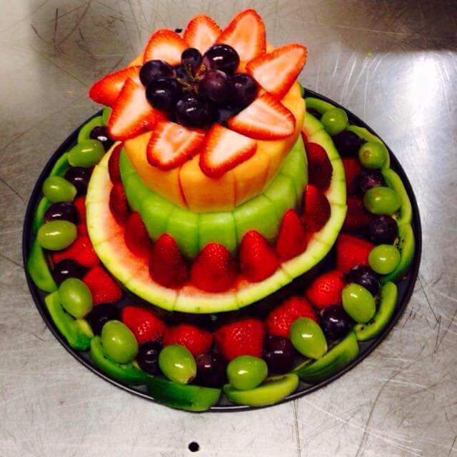 a fruit cake with strawberries and grapes on top