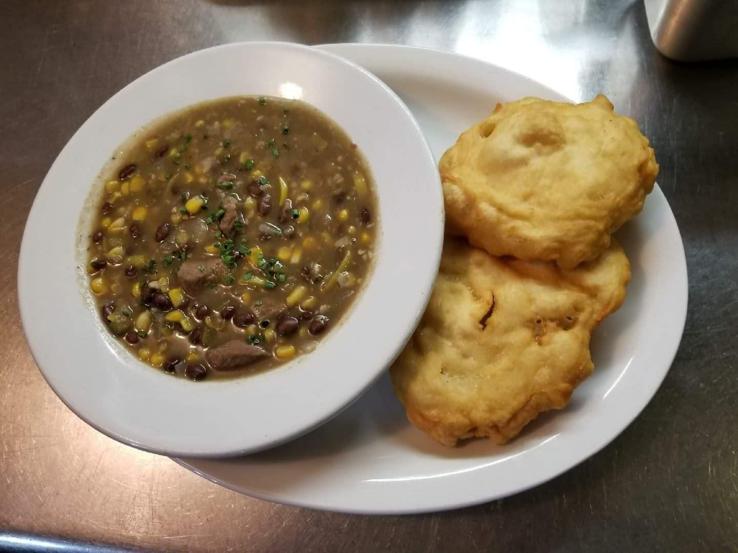 a white plate topped with a bowl of soup and fried biscuits