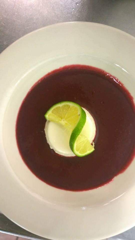 a white plate topped with a bowl of soup and a slice of lime .
