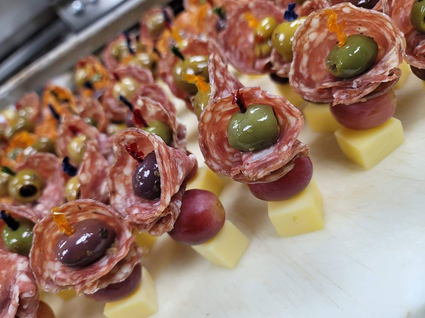a close up of a plate of food with meat , cheese , olives and grapes .