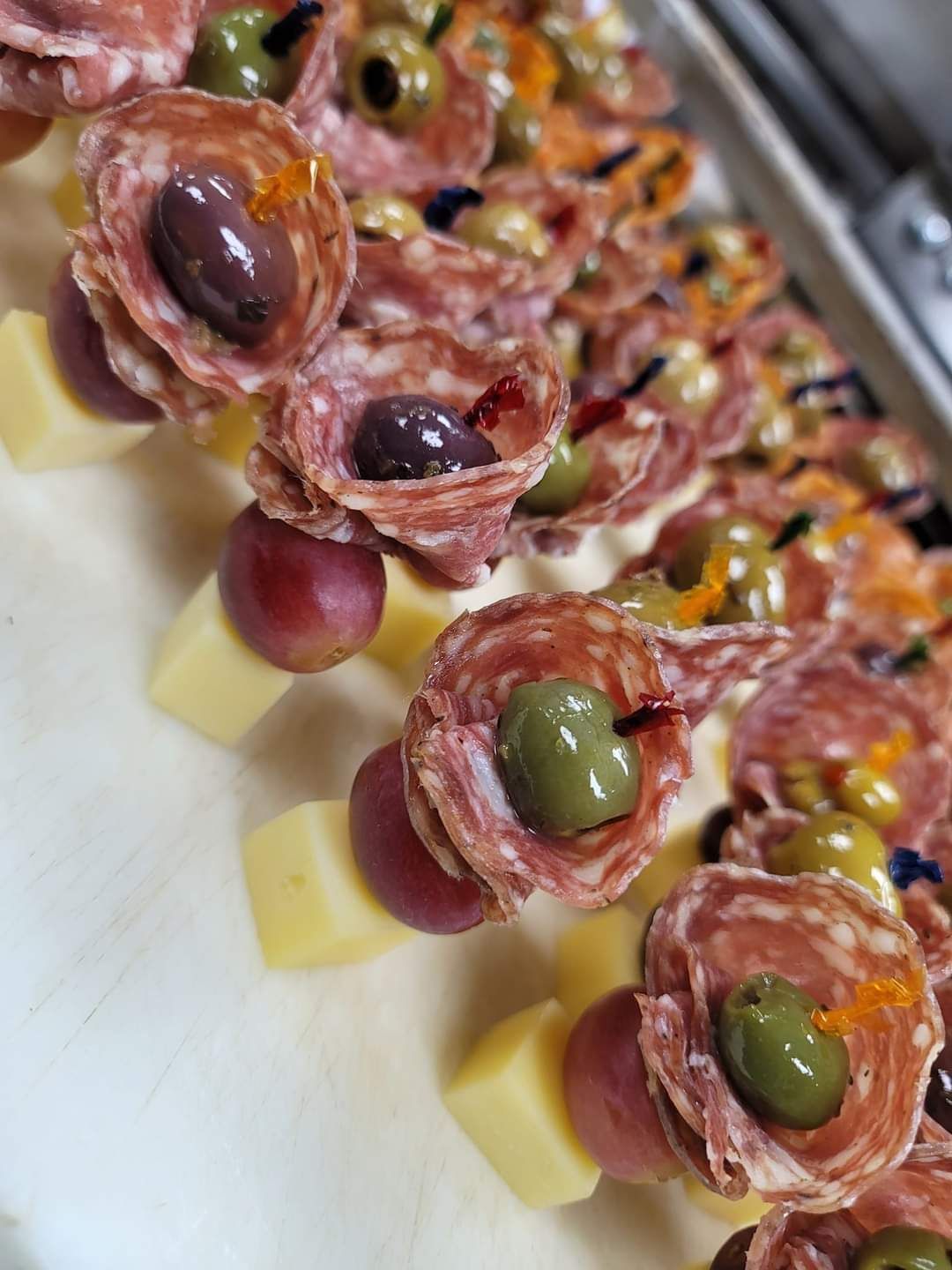 a close up of a plate of food with grapes , olives , cheese and salami .