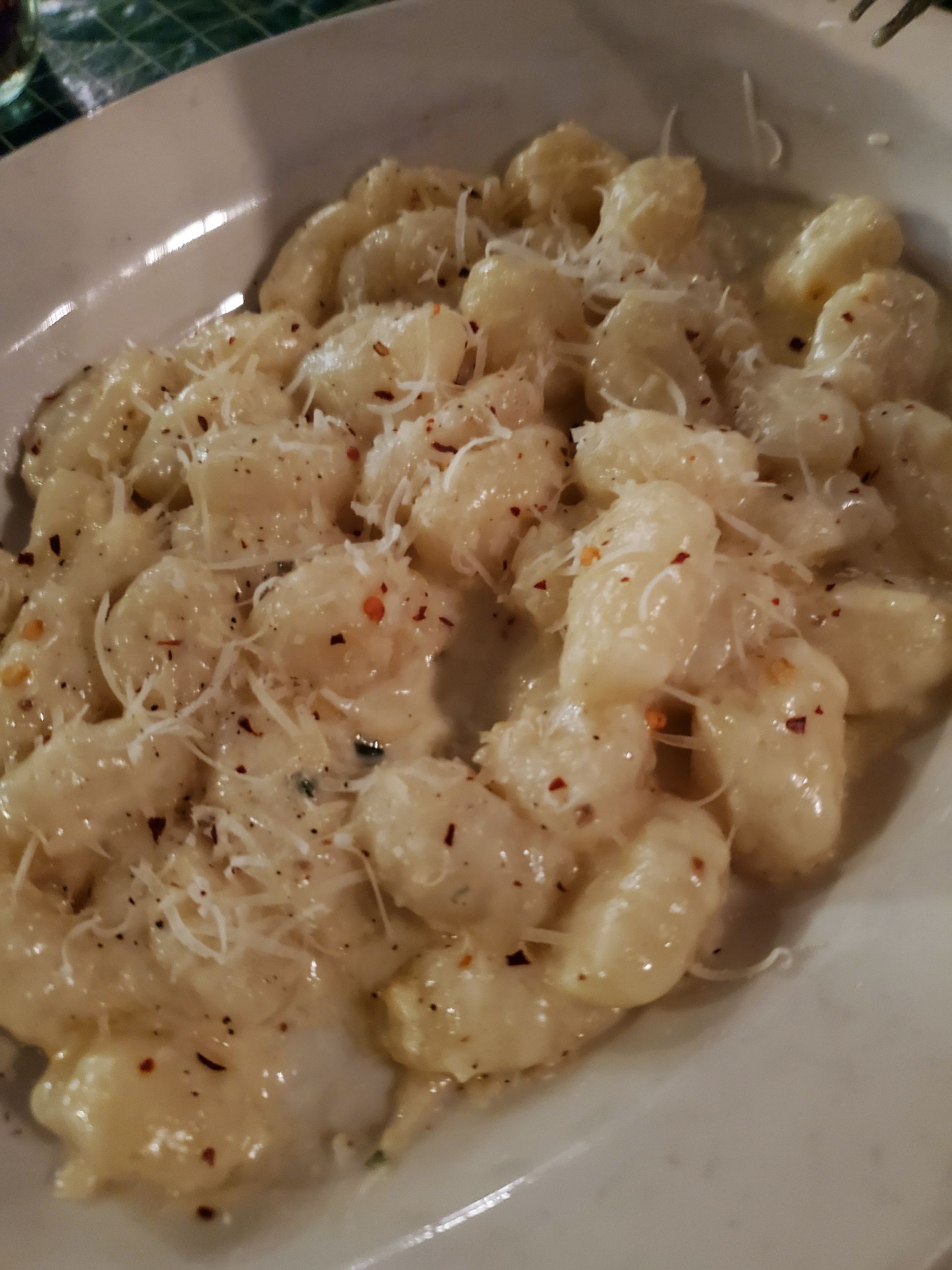 a white plate topped with gnocchi and cheese on a table .