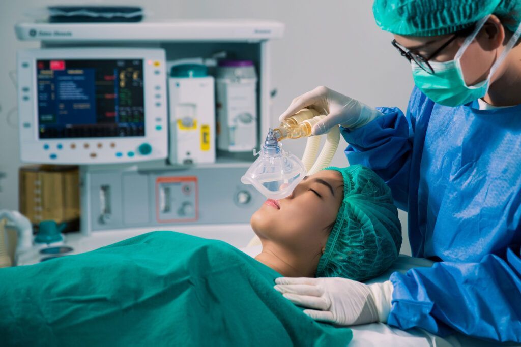 Anesthesiologist ventilating a patient in surgery with monitors and equipment nearby