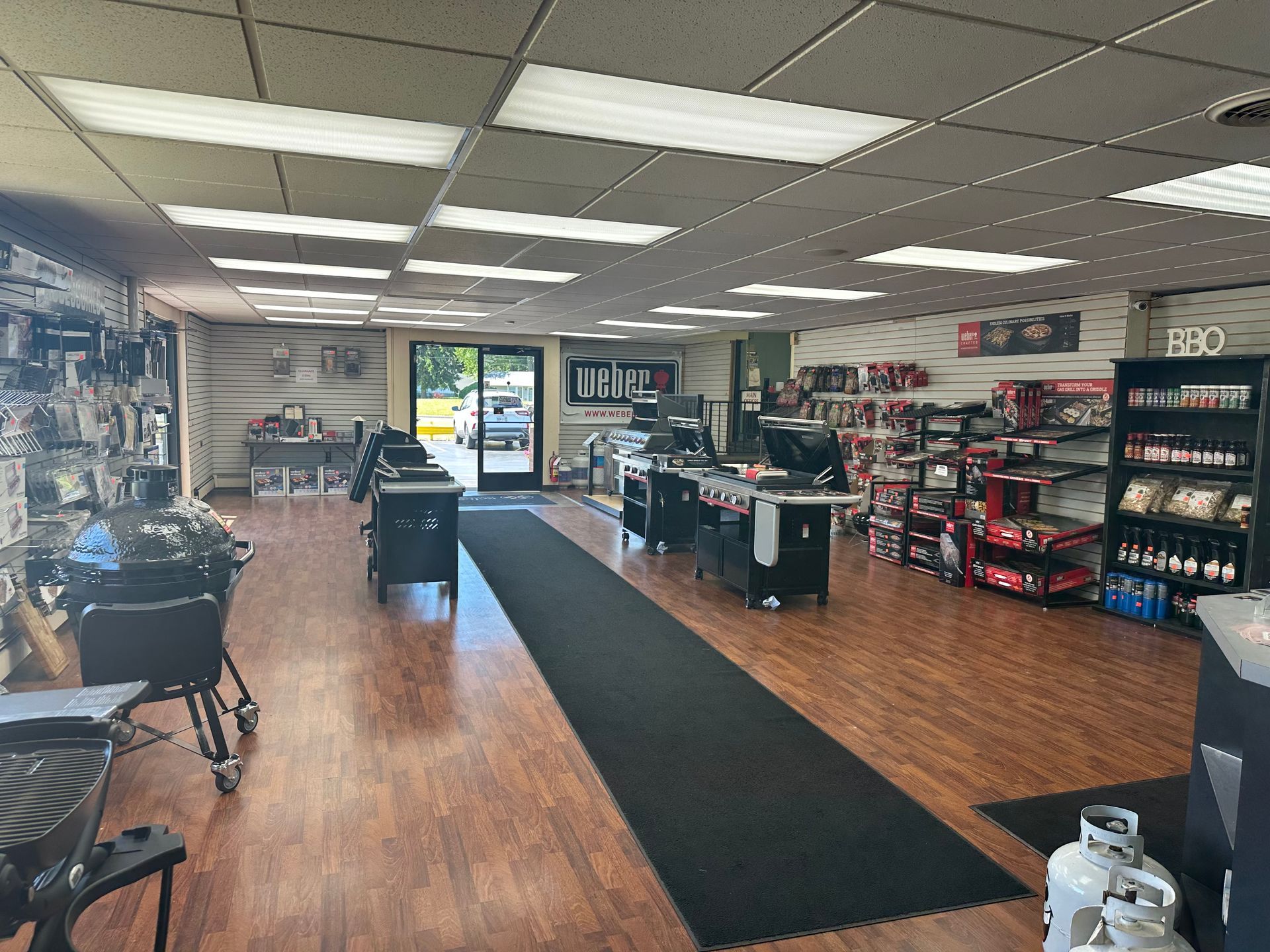 Interior of a small convenience store with wood floors, black checkout counters, and shelves of snacks and drinks.