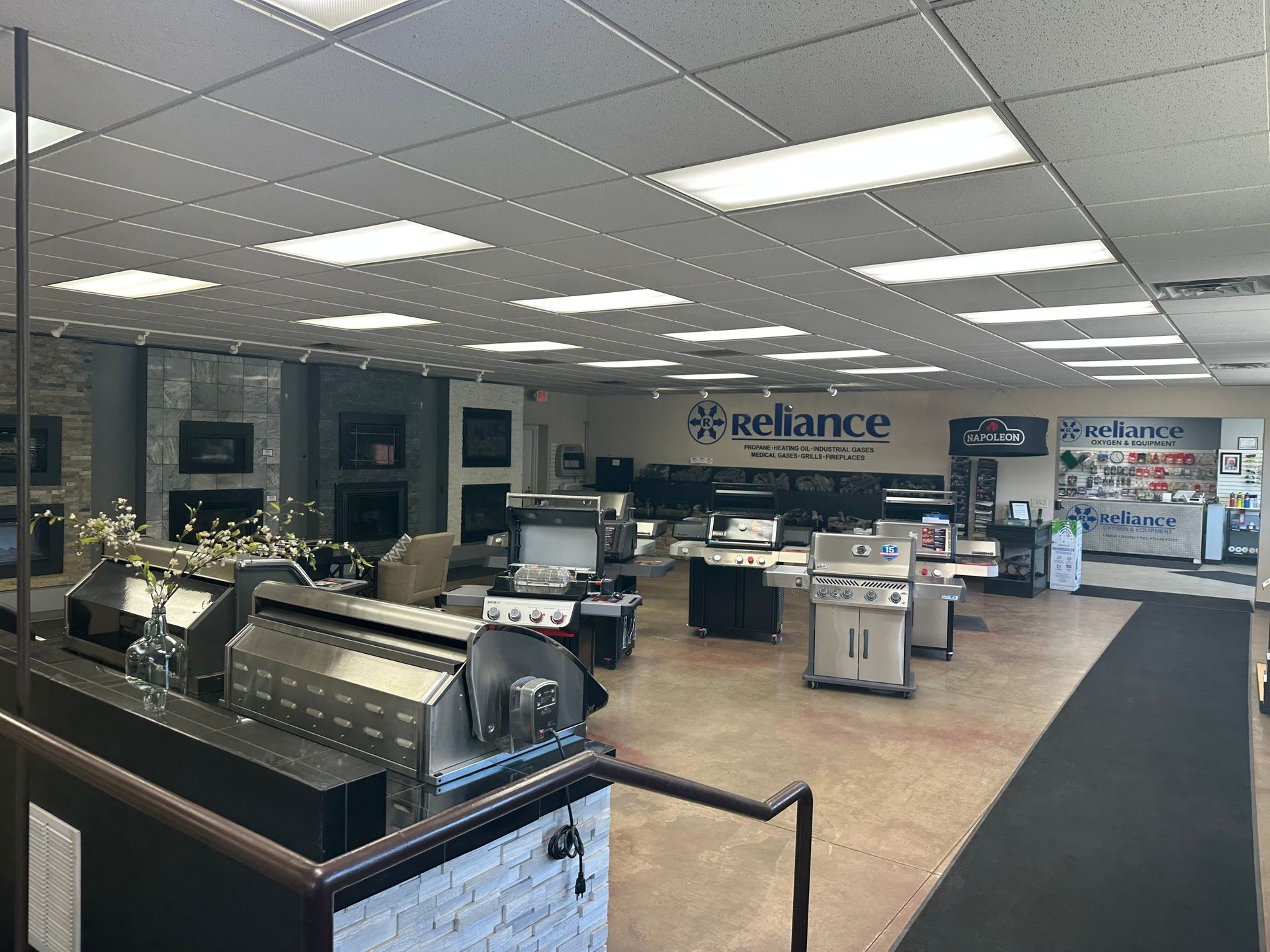 Interior of a retail showroom with ceiling lights, display counters, and a Reliance sign at the back.