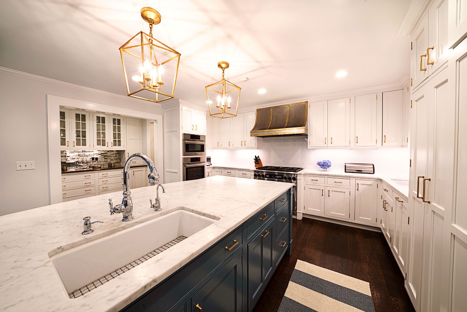 Bright, spacious kitchen with blue island, white cabinets, and gold light fixtures.