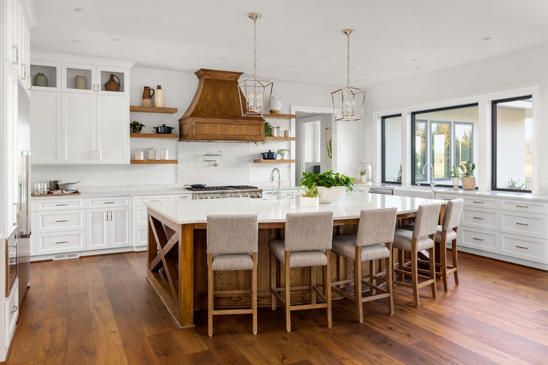 Spacious white kitchen with wooden island, countertops, and flooring; natural light.