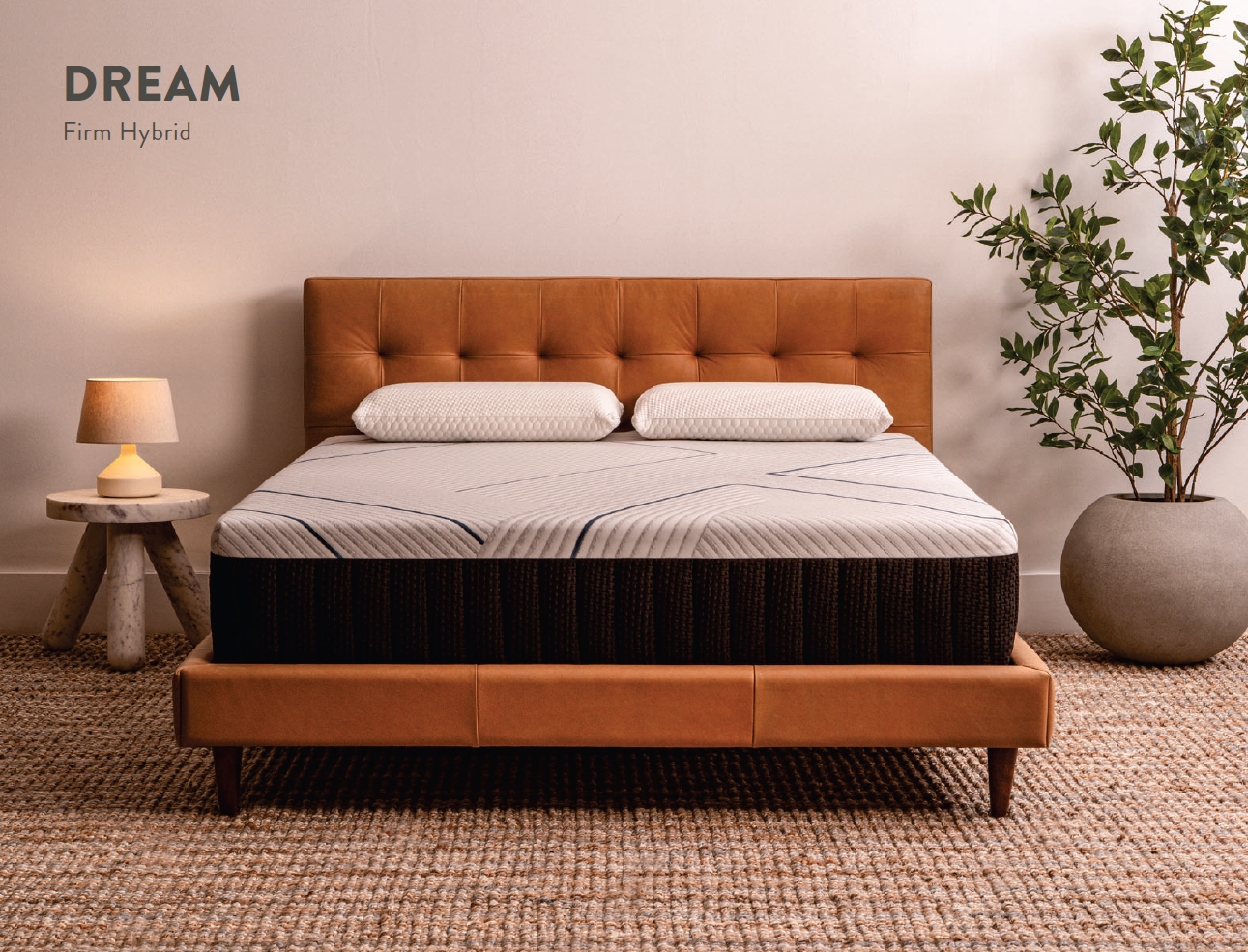 A bed with a brown leather headboard and mattress. Two pillows are on the bed, with a lamp on the side table.