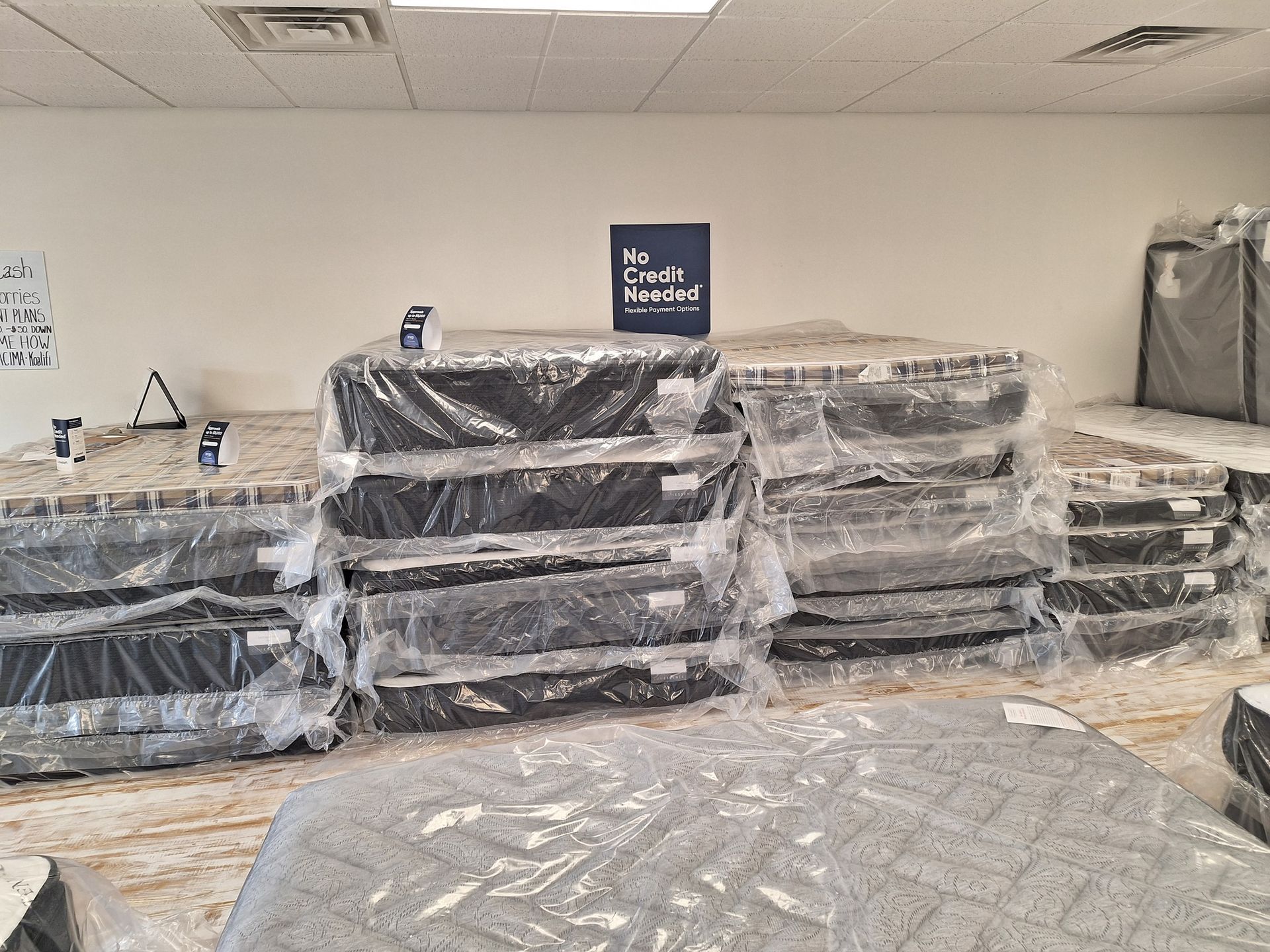 Mattresses wrapped in plastic stacked inside a retail store.
