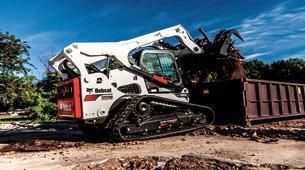 A bulldozer is loading dirt into a dumpster on a construction site.