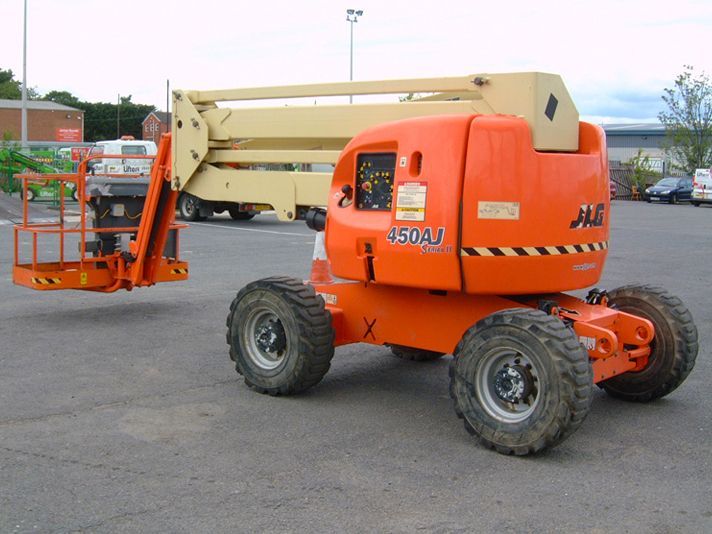 An orange jlg lift is parked in a parking lot